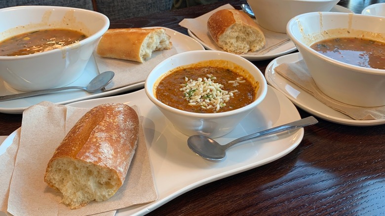Bowls of soup on plates with baguette breat on table at Panera