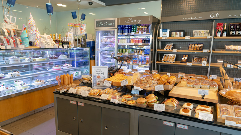 Interior of Paris Baguette bakery with fresh pastries and bread on display and more desserts behind glass counter