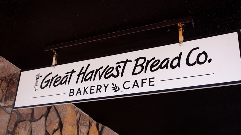 Great Harvest Bread Co. Bakery sign hanging outside store with stone wall