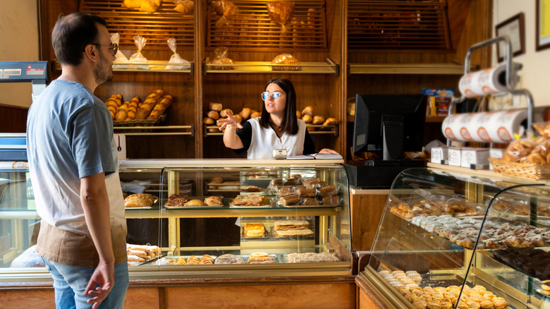 man waiting at counter of bake shop