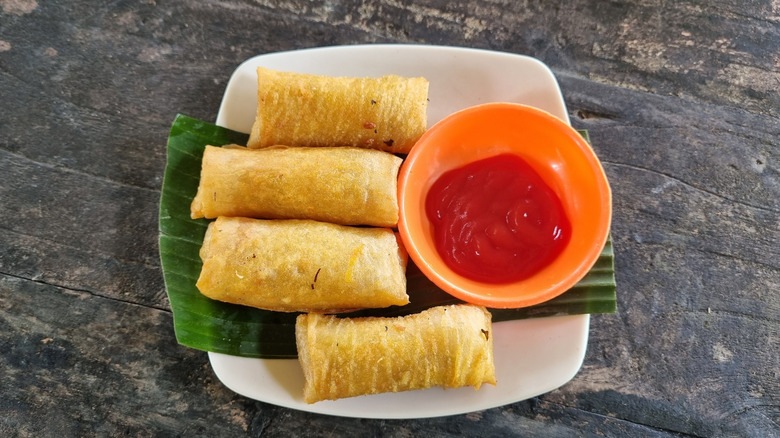 lumpia with banana ketchup on a white plate