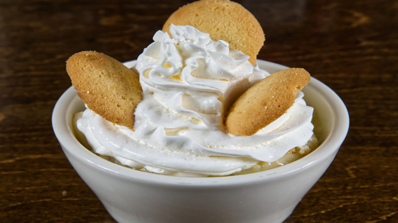 vanilla wafers and whipped cream on top of bananas in a small, white cup