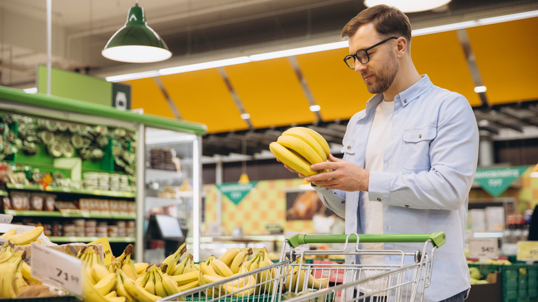 A man picks out a bunch of bananas at a grocery store