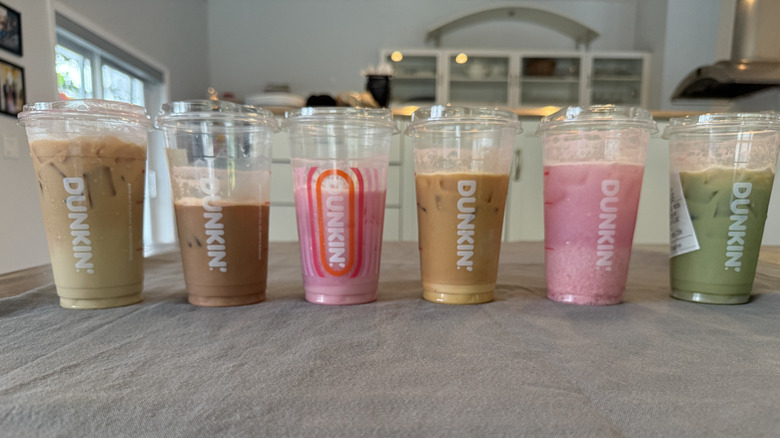 Six Barbie pink drinks from Dunkin' on grey tablecloth