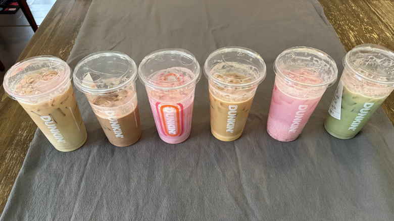 Top view of Six Barbie pink drinks from Dunkin' on grey tablecloth