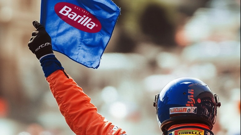 A race car driver waving a Barilla flag