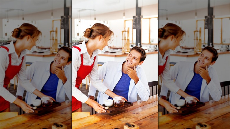 A male customer smiling and flirting with a female waitress or barista
