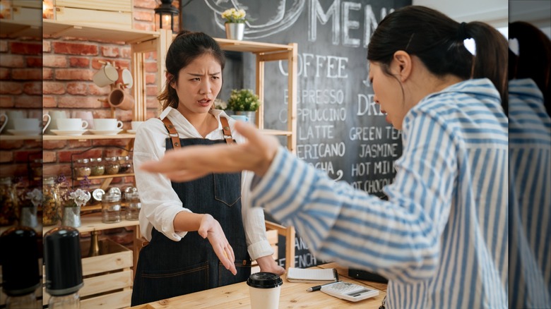 A customer arguing with a staff member at a coffee shop counter
