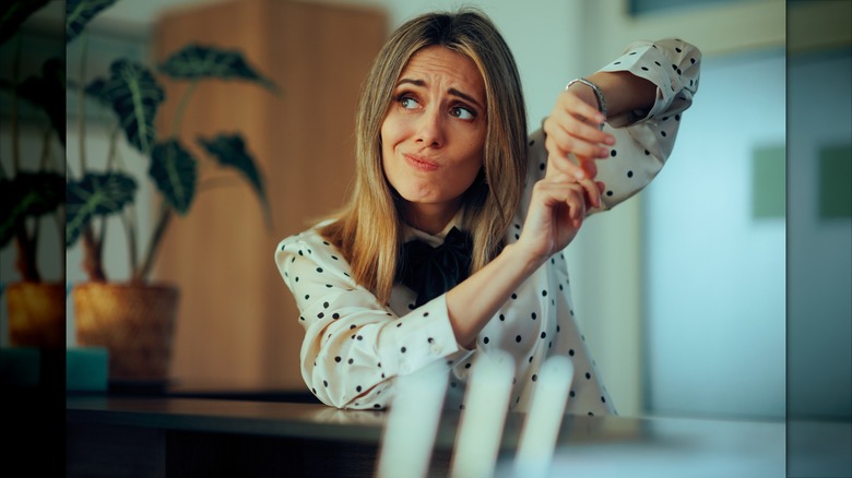 Woman waiting at the counter pointing at the time on her watch