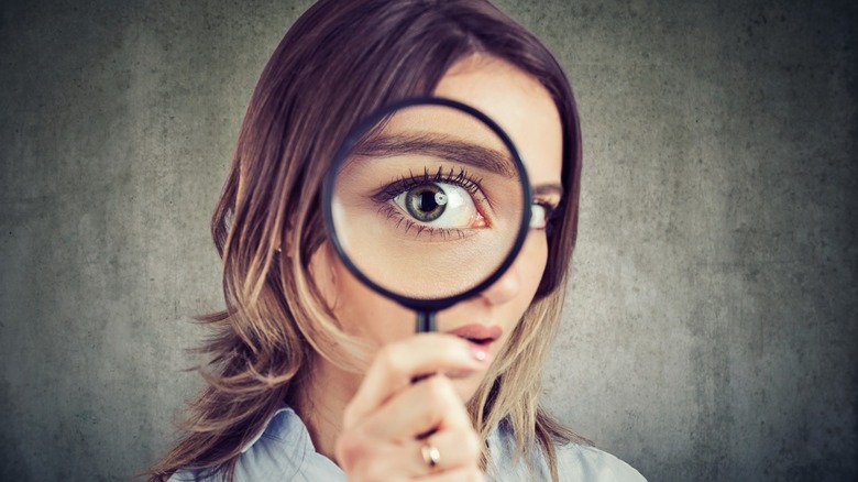 Curious young woman looking through a magnifying glass