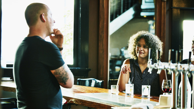 bartender scratching chin with customer