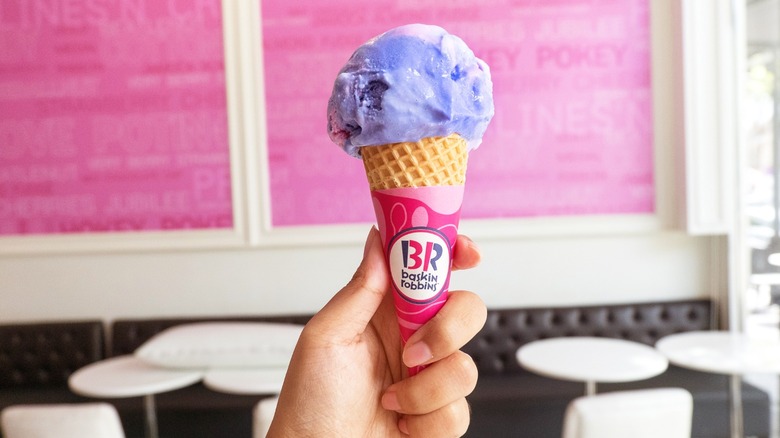 A hand holding a cone of purple ice cream from Baskin-Robbins.