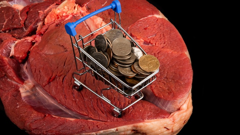 Steak with mini shopping cart filled with coins. Conceptual plot about the price of beef meat.