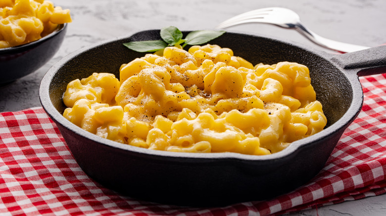 Mac and cheese in a cast iron pan on a picnic cloth.