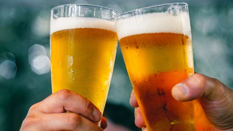 Two people clinking beer glasses together