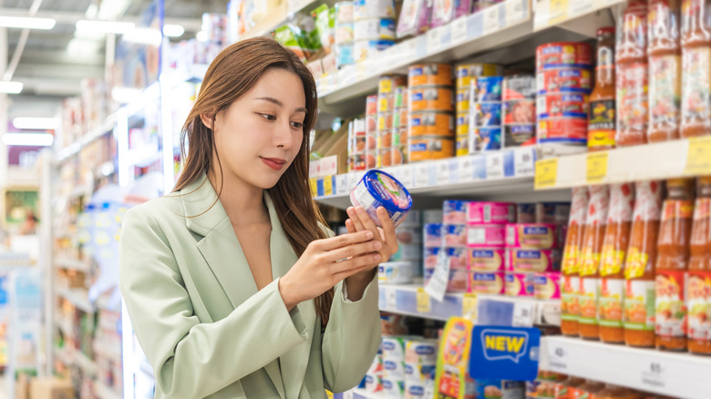 Person checking the label of tuna cans in the supermarket