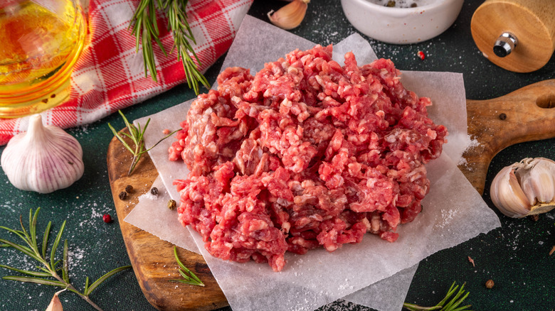 Ground meat on a cutting board next to garlic