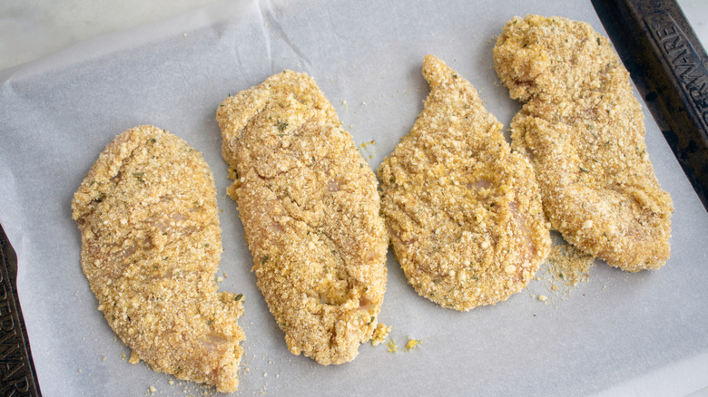 Raw chicken filets resting on a baking sheet