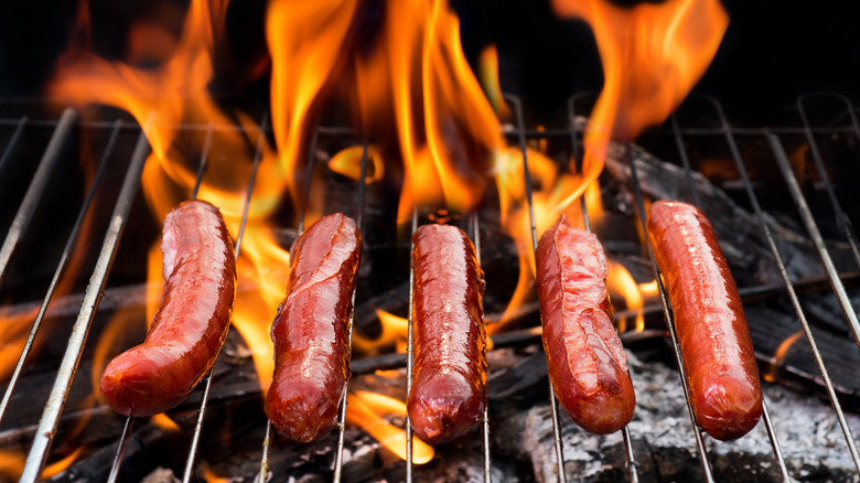 Hot dogs on a grill with flames in the background