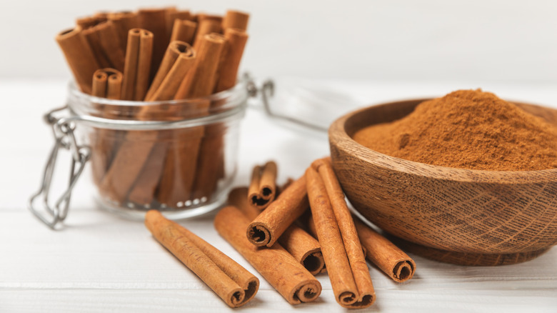 Cinnamon sticks in jar next to bowl of ground cinnamon