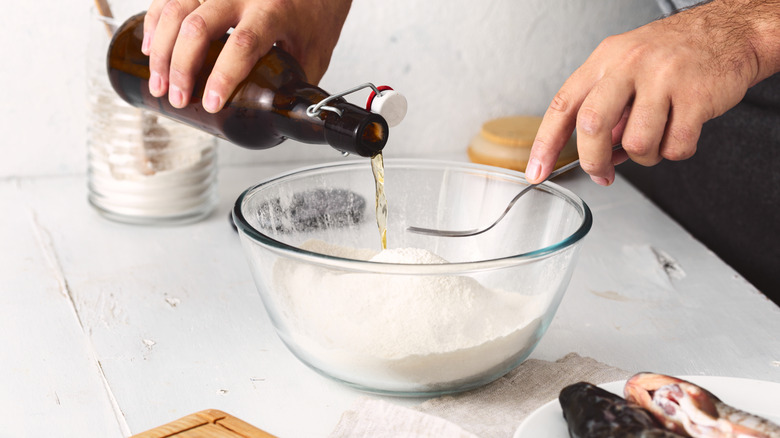 A home cook pours beer into a bowl of flour for a recipe