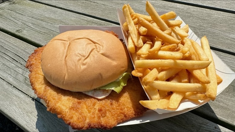 Pork tenderloin sandwich with fries in a to-go container
