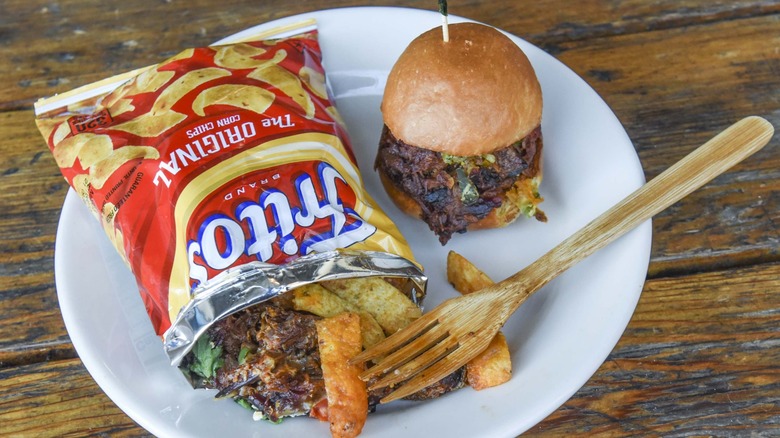 Frito pie in a bag with a slider on a white plate