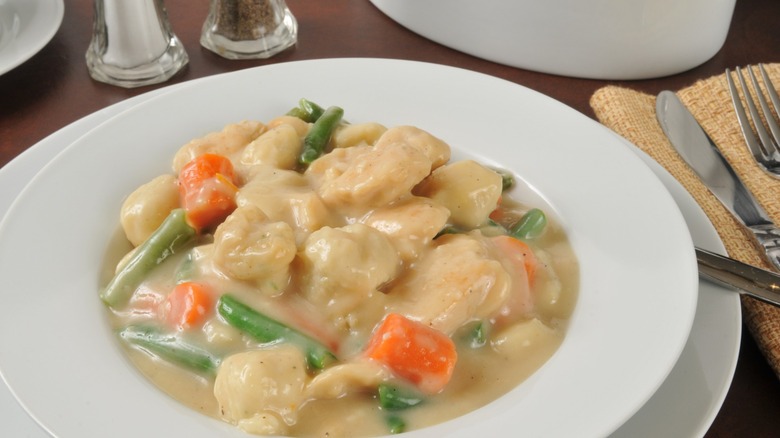 Closeup of a white bowl of chicken and dumplings