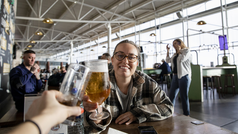 A woman at an airport restaurant clinking glasses with her tablemate