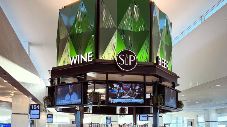 The sign for SIP Wine Bar inside San Diego International Airport with multiple TV's below it
