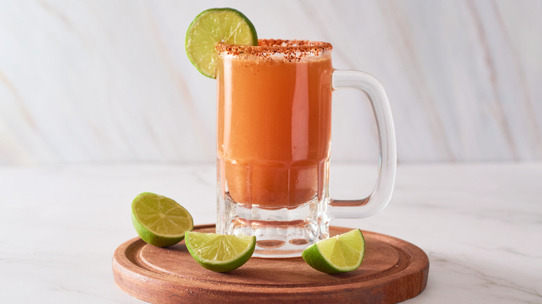 A michelada in a mug style glass with a slice of lime on the rim