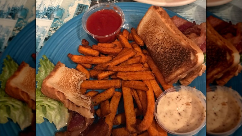 Izzy's Super BLT on a blue plate with fries and various sauces