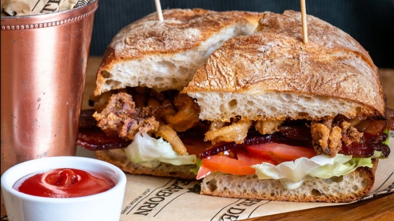 The Dearborn Fried Calamari BLT on paper with a bowl of ketchup