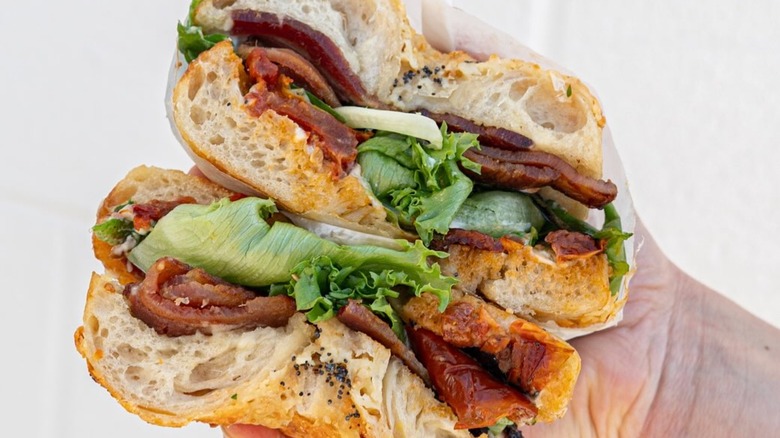 Hand holding a Bagelsaurus BLT