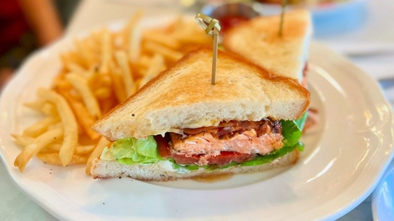 Heather's Minnetonka blackened salmon BLT with side of fries on a white plate