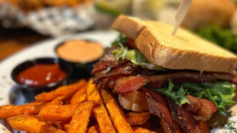 Heritage Bar & Kitchen B.B.B.B.L.T with fries and two sauces on a white plate