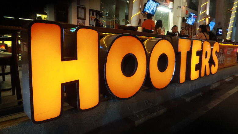 Hooters sign in orange in front of dining area