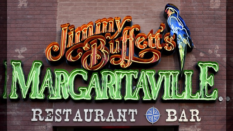 Exterior of Jimmy Buffett's Margaritaville with restaurant logo and blue parrot neon sign