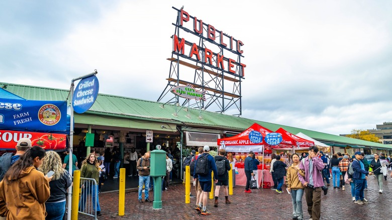 People are captured actively shopping and exploring the bustling aisles of the iconic Public Market Center Pike Place Market