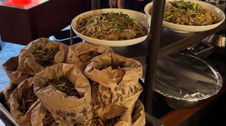 Brown paper bags filled with Seaweed "shake shake" fries and two plates of noodles from Tolo