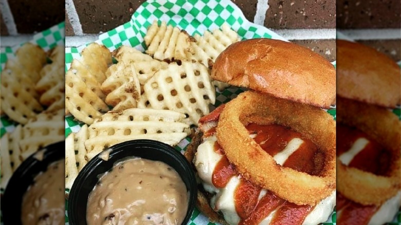 Waffle fries beside a burger and tub of sauce from The Hub