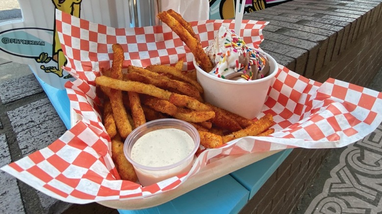 Dusted french fries with a side of dipping sauce beside a container of soft serve with sprinkles from Fryce Cream