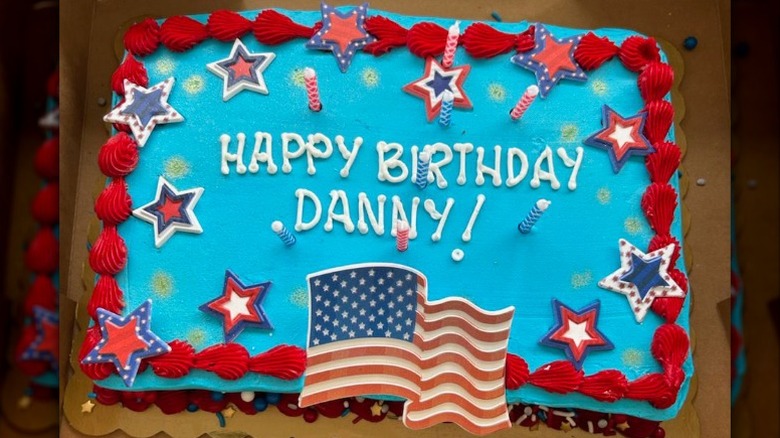 Blue-frosted sheet cake with red border and american flag and stars