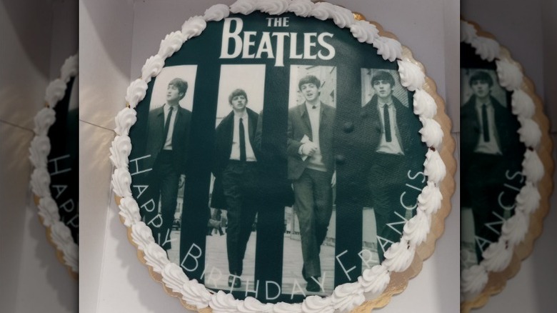 Round happy birthday cake with a picture of The Beatles and white border