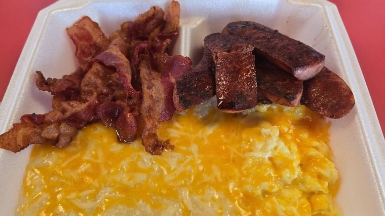 Eggs, bacon, and breakfast meat from Greg's Breakfast Bar in takeout styrofoam container