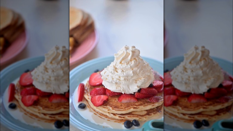 Stack of pancakes with whipped cream and fresh fruit on plate at The Agave Diner