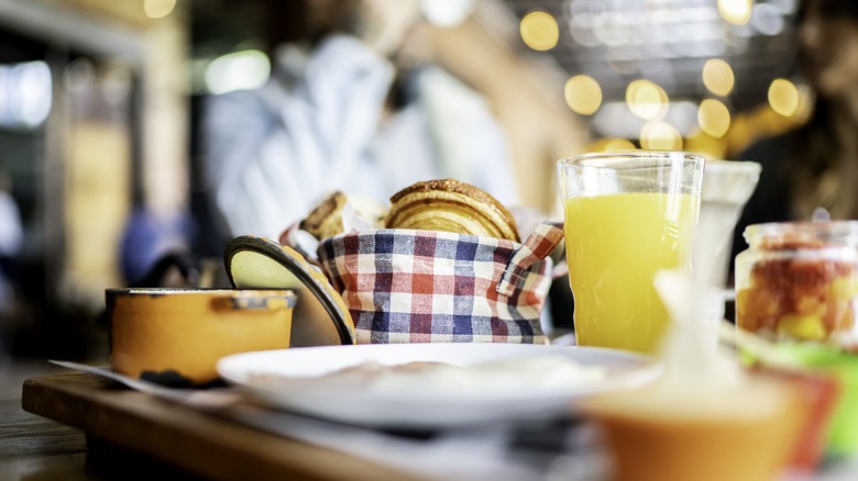 Serving tray full of breakfast foods with glasses of juice and croissants
