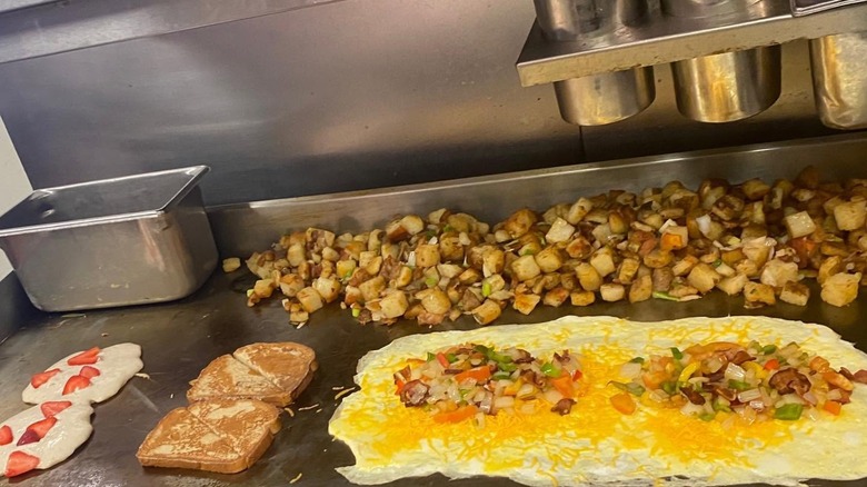 Breakfast foods like pancakes, French Toast, omelets, and hash browns being prepared on the flat top grill at Louie's Cafe