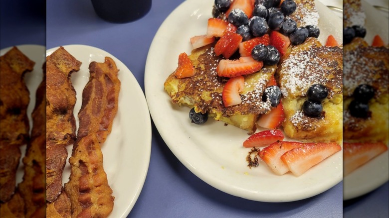 Plate of bacon strips beside a plate of French Toast with Fresh berries at Lucille's Country Cooking