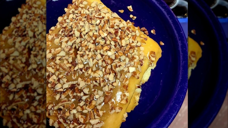 Jumbo Warm Caramel Roll topped with nuts on blue plate at Darcy's Cafe